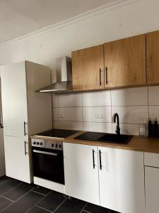 a kitchen with white cabinets and a black stove top oven at Hirschquartier in Hachenburg