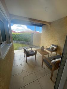 a living room with a table and chairs and a window at La Villa Nature in La Plaine des Cafres