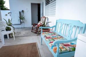 a blue bench sitting on a porch with two chairs at Cozy West Coast Studio in Cabo Rojo