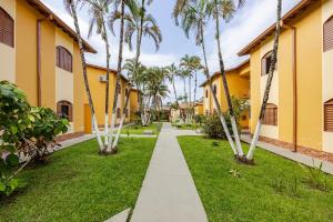 a walkway through the courtyard of a building with palm trees at Casa a 500m da Praia do Sape in Ubatuba