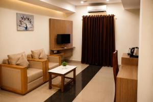 a living room with a couch and a tv and a table at Hotel Sakthi in Kottayam