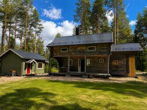 a log cabin with a green house in a yard at Cabin in the Woods in Malung