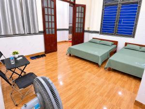 two beds in a room with wooden floors and windows at Phòng nghỉ 24h in Trung Nghĩa