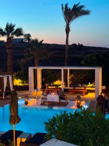a villa with a pool and palm trees at night at Aurora Luxury Suites in Imerovigli