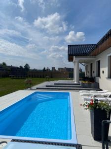 a swimming pool with chairs and a house at Dworek pod Krzyżtoporem Ujazd Agroturystyka- pokoje do wynajęcia in Iwaniska