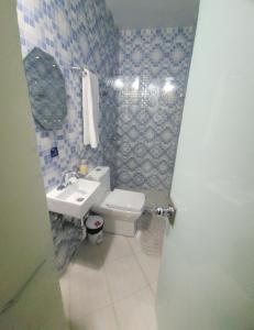 a bathroom with a white toilet and a sink at Vincent Suites Hotel in Pasto