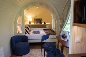 a bedroom with a bed and two blue chairs at Les Nuits de Thoiry in Thoiry