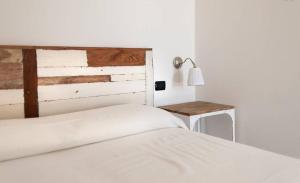um quarto com uma cama branca e uma cabeceira em madeira em Casa Serradei em Torchiarolo