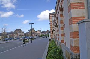 a street next to a building with cars parked at Hôtel MAEN-HIR Dol Gare in Dol-de-Bretagne