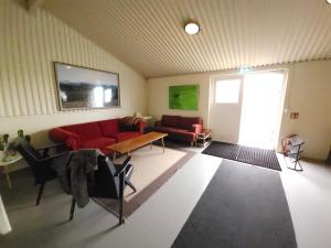 a living room with a red couch and a table at Kaldbakur Guesthouse in Heimaland
