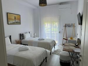 a white room with two beds and a window at Ilvi Guesthouse in Gjirokastër