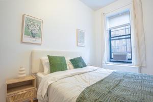 a white bedroom with a bed and a window at Charm 2Bd in Upper East Side with Backyard in New York