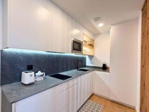 a kitchen with white cabinets and a black counter top at YourHouse O Foxo in Allariz +6 photos