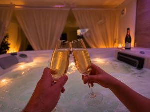 two people holding champagne glasses in front of a tub at Le Bain des VioIettes - Grand jacuzzi privatif in Dole