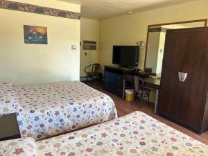a hotel room with two beds and a desk and a television at Motel R-100 in Longueuil