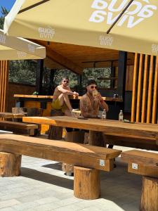 two people sitting at a picnic table with drinks at Maglian Forest Retreat in Divčibare