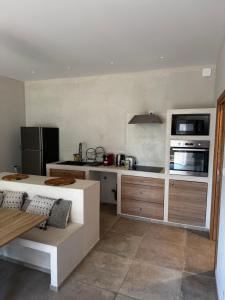a kitchen with a stove top oven and a microwave at Rez-de-villa 65m2 climatisé in Propriano