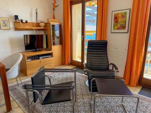 a living room with four chairs and a television at Parco Esotico by HolAp SA in Brissago