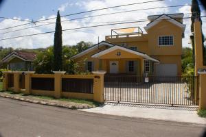 a yellow house with a black fence at The Vista Inn Studio #4 in Falmouth