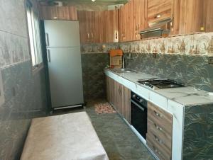 a kitchen with a white refrigerator and a stove at Kaltouma in Sidi Bibi