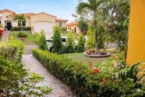 a garden in front of a house with a palm tree at Tamarindo Village in San Carlos
