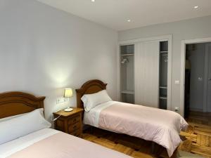 a bedroom with two beds and a table with a lamp at Apartamentos Jayo in Nueva de Llanes