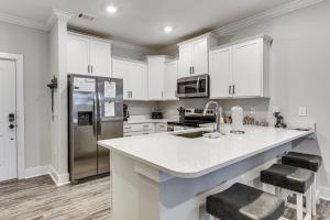 a kitchen with white cabinets and a stainless steel refrigerator at Golf + Poolside Days! Condo 9 Mi to Sunset Beach in Calabash