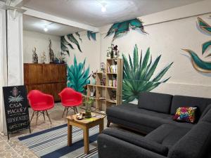 a living room with a couch and red chairs at Hostel Casa Maguey in Oaxaca City