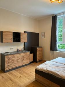 a bedroom with a bed and a kitchen with cabinets at Gästehaus Lelo 1 in Solingen