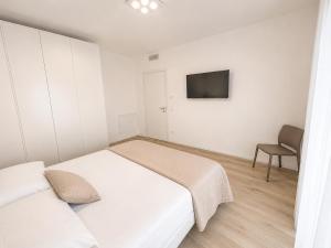 a white bedroom with a bed and a chair at Haus Margarete - Agenzia Cocal in Caorle +15 photos