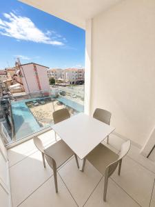 a white table and chairs on a balcony with a window at Haus Margarete - Agenzia Cocal in Caorle