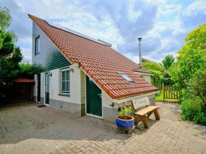 a small house with a red roof and a bench at Gezinsvriendelijk natuurhuis De Kraanvogel in Appelscha