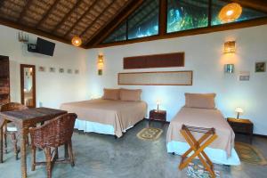 a bedroom with two beds and a table and chairs at Serena Pousada - Icaraí de Amontada in Icaraí
