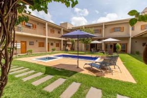 a patio with an umbrella and chairs and a pool at Pousada das Bandeiras in Olímpia