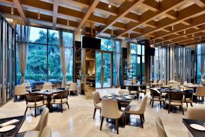 ein Restaurant mit Tischen und Stühlen und großen Fenstern in der Unterkunft Indore Marriott Hotel in Indore