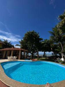 a large blue swimming pool in front of a house at Pousada Marauá - Na beira do mar de Cumuru in Cumuruxatiba