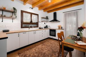 a kitchen with white cabinets and a wooden table at Epi tis Stigos in Kalavrita