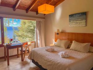 a bedroom with a bed and a table and a window at Pailahue Cabañas Lodge in San Carlos de Bariloche