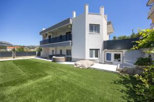 a large white house with a dog laying on the grass at Lux suite in Split- Jacuzzi&Gym&more in Solin