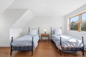 two beds in a white room with a window at Oceanfront House Steps to Water in French Village