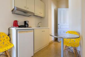 a small kitchen with a table and yellow chairs at Mimoza in Spetses