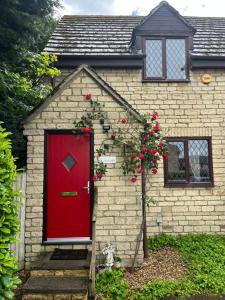 a red door on a brick house with a tree at Hideaway Cottage in Bourton on the Water +3 photos