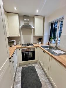 a kitchen with white cabinets and a stove top oven at Hideaway Cottage in Bourton on the Water