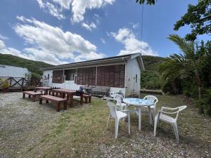 eine Terrasse mit Tischen und Stühlen und ein Gebäude in der Unterkunft beach house in Amami