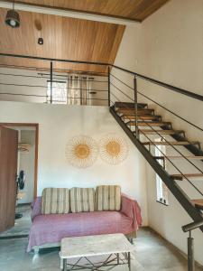 a living room with a couch and a staircase at Girassóis do Vale - Chalés no Vale do Capão in Caeté-Açu