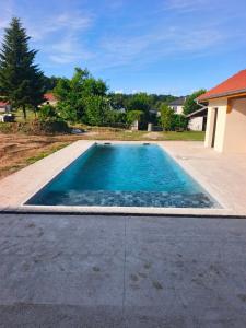 a swimming pool with blue water in a yard at La Petite Écurie in Soleymieu