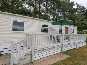 a house with a deck with a table and an umbrella at Foxglove 4 in Ringwood