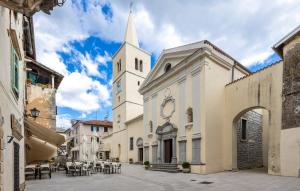 a church with a tall white tower with a steeple at Apartment old Town in Lovran +5 photos