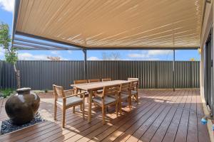 a patio with a wooden table and chairs and a vase at The Grand Aveley House in The Vines
