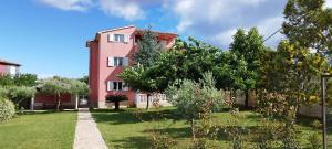 a pink house with a garden in front of it at Apartmani Volme in Banjole